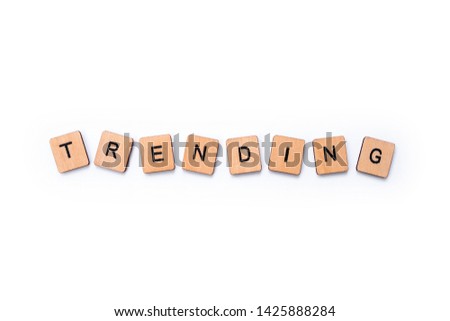 The word TRENDING, spelt with wooden letter tiles over a white background.