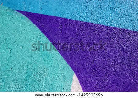 The wall is painted with bright different colors. Clear contours and bright colors on a plastered wall with a rough texture. Colorful background with a heterogeneous texture of the material.
