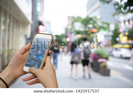 Mockup image, people lifestyle, GPS pin and map satellite navigator apps concept. Woman using mobile smart phone searching location via mobile application with blurred background of people in the city