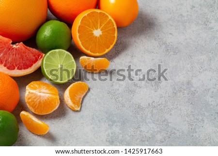 group of whole and sliced citrus fruits - tangerines, lemons, limes, oranges, grapefruits on the surface of the gray table - image with copy space