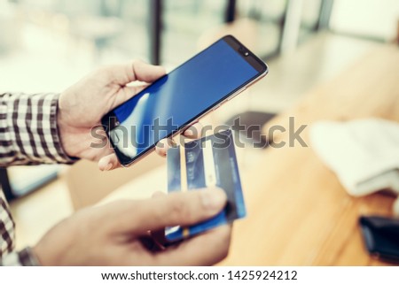 Young man hand holding a credit card and using smart phone for payment online order. Asian people.