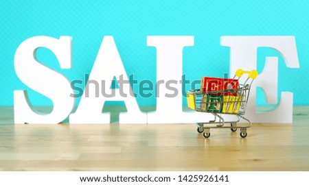 End of Financial Year sales shopping concept with mini shopping cart and large sale letters.