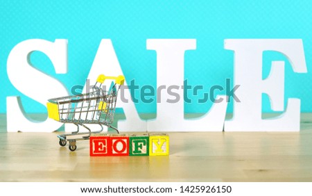 End of Financial Year sales shopping concept with mini shopping cart and large sale letters.