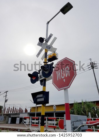 Thai railway crossing with the red stop sign and light signal; Translation: "STOP" on the red stop sign and "Beware of train" on the white crossing label