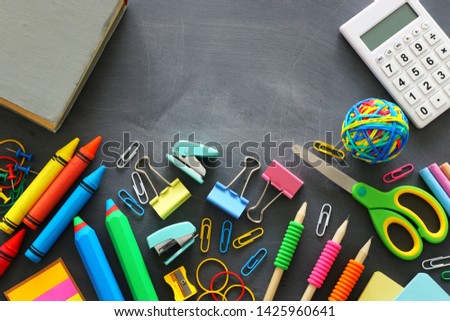 education and back to school concept. stationery and book over classroom blackboard. top view, flat lay