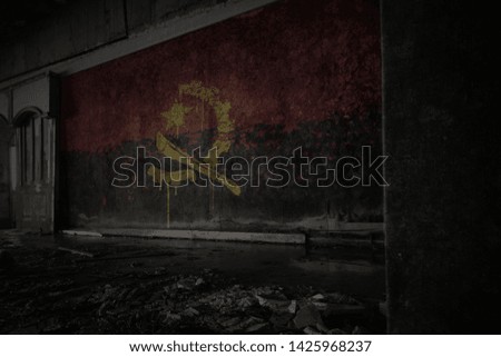 painted flag of angola on the dirty old wall in an abandoned ruined house. concept