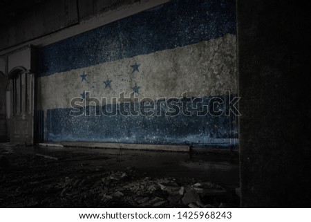 painted flag of honduras on the dirty old wall in an abandoned ruined house. concept