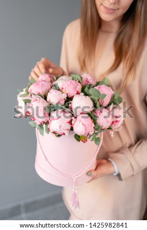 Pink peonies in pink round box. Beautiful peony flower in womans hands for catalog or online store. Floral shop concept. Flowers delivery