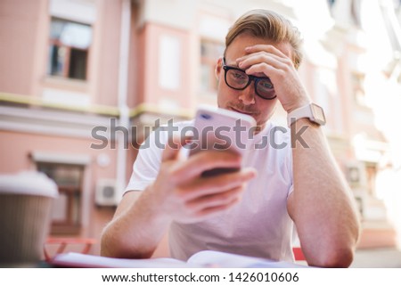 Serious Caucasian man in classic eyewear reading received email with bad news solving problems during online communication with customer service, unhappy male have mistake with money transfer Royalty-Free Stock Photo #1426010606