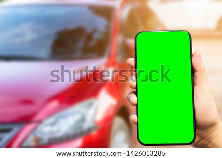 Close-up of female use Hand holding smartphone blurred images touch of Abstract blur of headlight ,window of red car outdoor background,green screen.