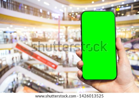 Close-up of female use Hand holding smartphone blurred images touch of Abstract blur of inside shopping complex background,shopping online concept,green screen.
