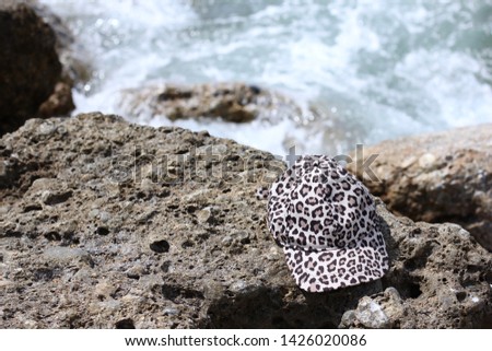 Cap on the beach. Cap left on the rocky shore near the sea. Tropical vacation and relax travel concept. Leopard print cap. Mediterranean sea, Turkey. Forgotten thing.   