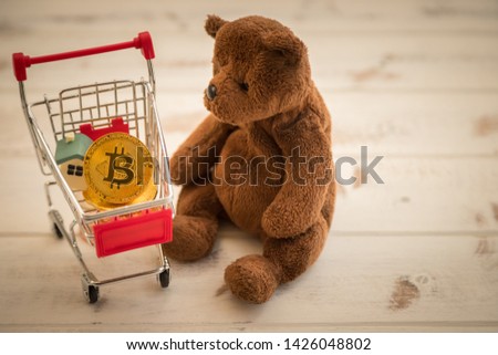 Bit coins in the car are used for payment transactions and brown teddy bear with a white wood background.