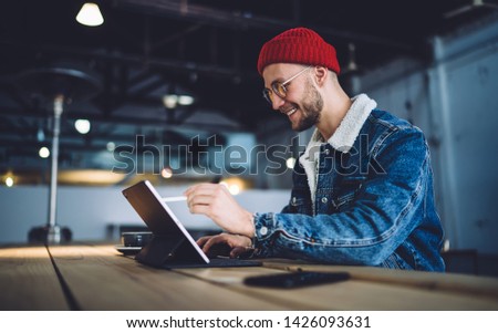 Cheerful male artist using smart stylus for drawing picture on tablet touch screen device connected to 4g wireless in coworking space, talented graphic designer working remotely with modern technology