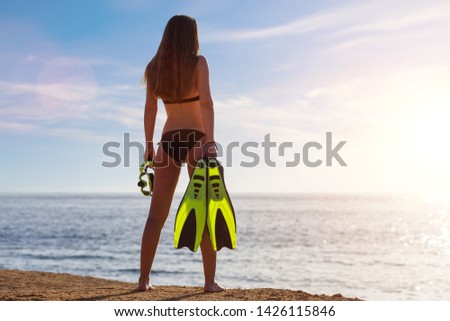 Young beautiful girl standing with snorkel and flippers near the sea. Tropical vacation snorkelling background with copy space