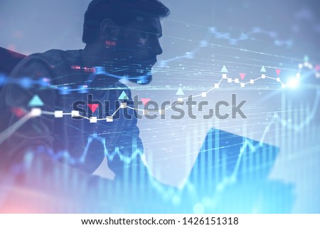 Serious young trader with beard working with laptop over white background with double exposure of forex charts. Concept of start up and stock market. Toned image blurred Royalty-Free Stock Photo #1426151318