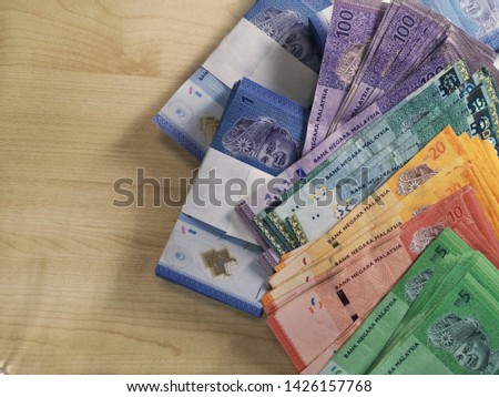 Various values ​​of Malaysian Ringgit banknote are scattered on wooden tables to count.