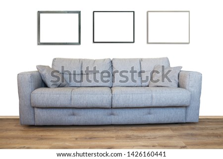 Interior of living room with sofa or couch furniture on wooden floor and three mockup art frames isolated with white wall background