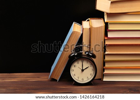 Vintage books and clock on wooden table - Image 