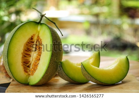 Whole and sliced of Honeydew melons,honey melon or cantaloupe (Cucumis melo L.) on wooden table with blurred garden background.Favorite fruit in summer.Food,Fruits or healthcare concept. Royalty-Free Stock Photo #1426165277