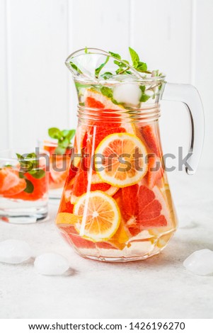 Grapefruit lemonade with lemon and mint in a glass jug.
