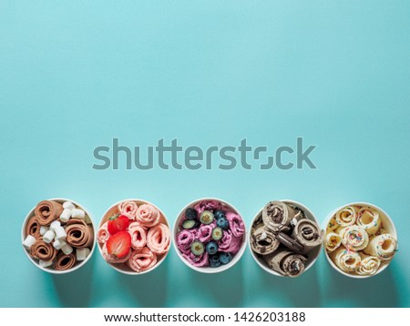 rolled ice creams in cone cups on blue background. Different iced rolls top view or flat lay. Thai style rolled ice cream with copy space for text or design