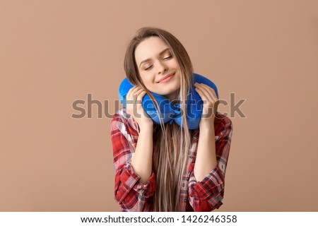 Young woman with travel pillow on color background Royalty-Free Stock Photo #1426246358