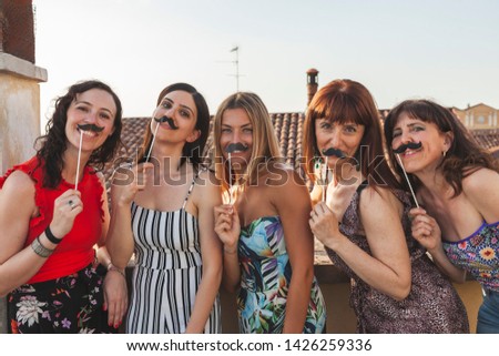 group of female friends having fun with party accessories on the roofs between the hanging laundry - concept of celebration and holiday