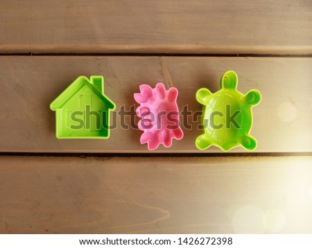 Children's toy green house, pink crab and green turtle on the wooden floor of a country house. Sun glare. Horizontal orientation, space for text.