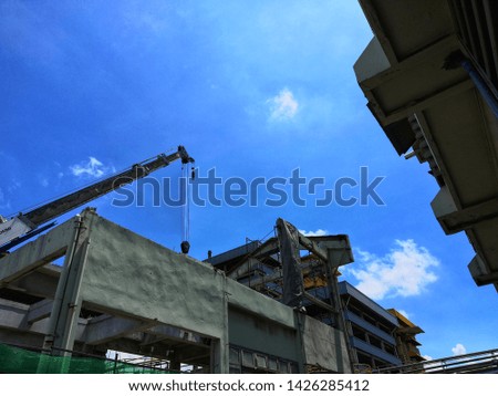 Old factory building and cranes in sunny day with white clouds background.