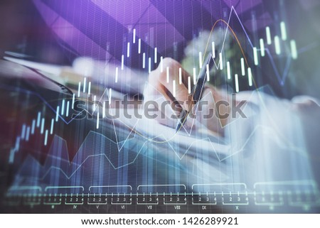 Financial forex graph displayed on hands taking notes background. Concept of research. Multi exposure