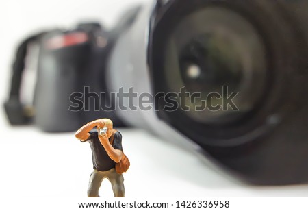 Miniature people are pretending to shoot and blur the DSLR background. copy space.