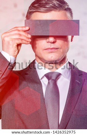 Mature businessman covering eyes with paper against wall at office