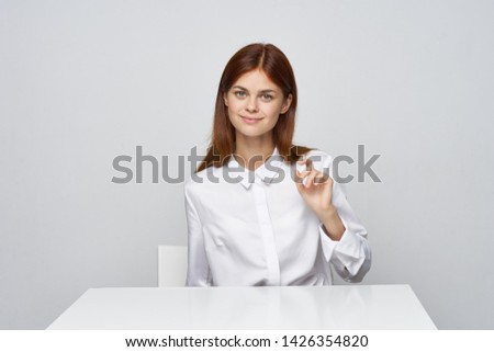 Emotional woman in a white shirt gesticulates with her fingers desktop office work