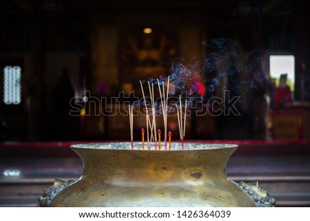 Joss stick or incense sticks burning by fire with smoke for buddhist pray for benefaction worship to Buddha at Thai or Chinese temple