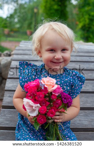 cute blonde girl is holding a bouquet of flowers