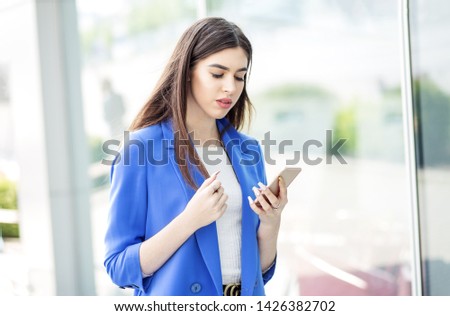 Beautiful brunette woman uses the internet on the phone. The concept of fashion, business, communication and lifestyle.