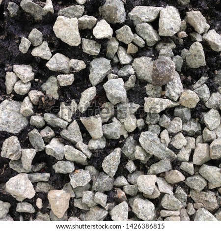 Macro photo of crushed stone and gravel on the ground. Texture background white stones on a black earth background. Image of broken stones