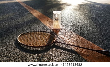 Badminton racket, shuttlecock in plastics box on thr floor and sun light.