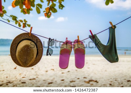 straw hat, sunglasses and swimsuit are dried on a rope on the beach. Conceptual photo about a trip to the sea.