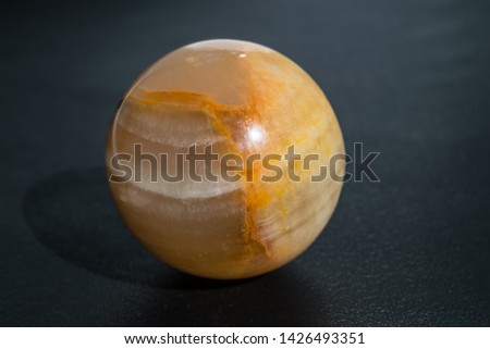 Opal moonstone yellow in the shape of a sphere of a ball on a black background close-up
