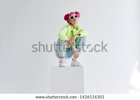 woman with a haircut in glasses sits on a cube