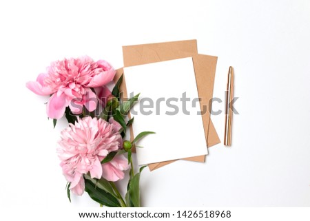 Creative mockup of craft envelope with a sheet of paper with a bouquet of pink peonies on a gray background