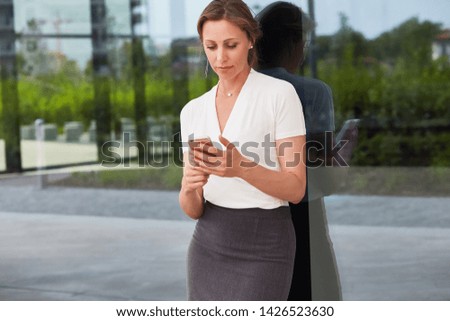 Woman with phone at the glass wall