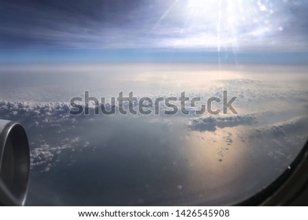 Airplane window overlooking the beautiful clouds and the earth. Sunset in flight on vacation. Tourist theme. Stock photo