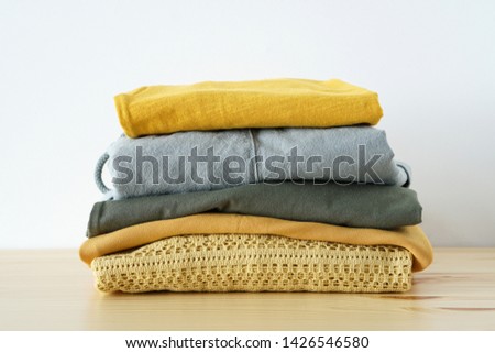 Folded clothes in yellow green gamma on wooden table and white background isolation