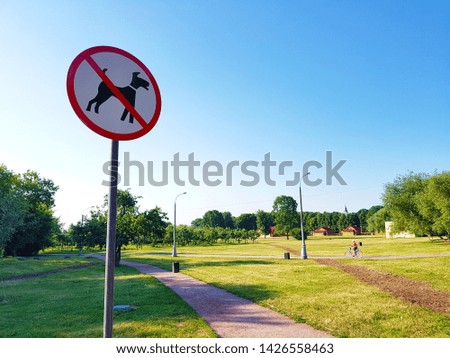 The animal pets disallow warning caution traffic sign in public natural park, with blue sky as background.
