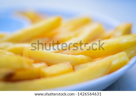 Close-up pictures of golden yellow potato chips or french fries that look appetizing on a white dish as a food backdrop composition.