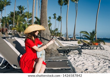   woman in a hat in a dress sits on the beach summer island                            