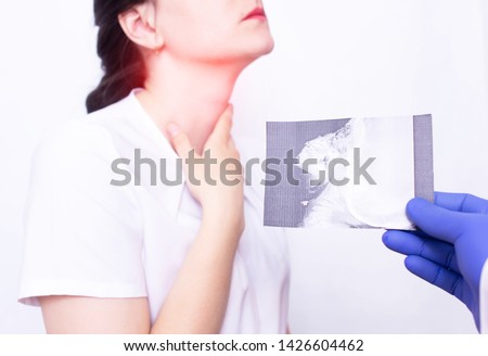 Dr. ENT holds an X-ray picture on the background of a young girl who has inflammation and sore throat due to adenoids, inflammation of the tonsils, medical